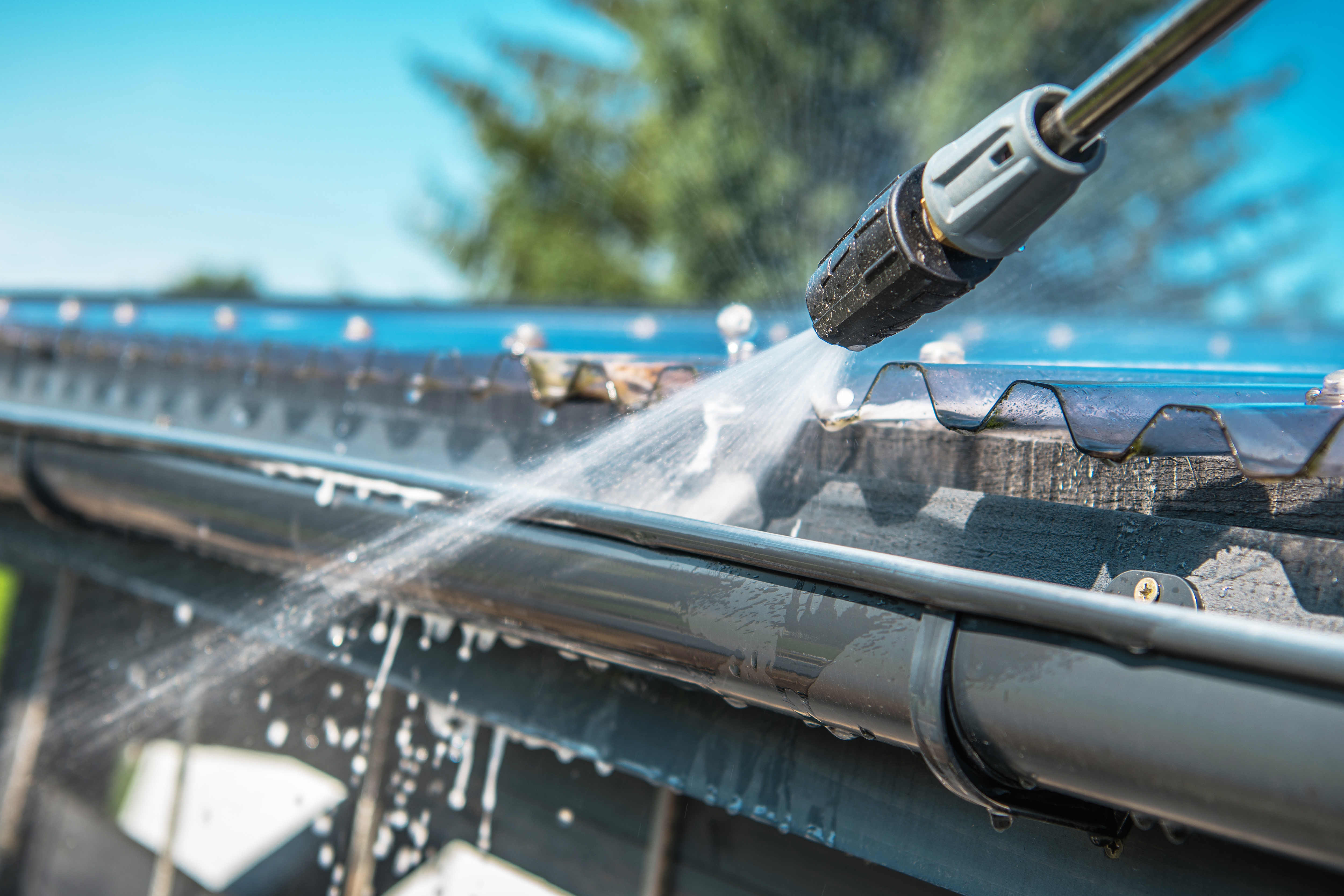 Pressure washing black gutters on house